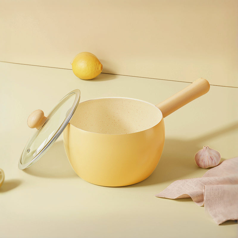 Cute and pretty yellow pot with wooden handle and lid on a light surface, solo cooking, Mini pot with Ceremic coating, non-stick.