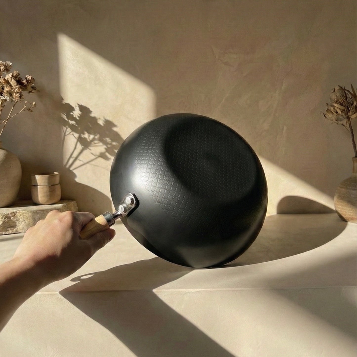 Person using a tool to open a black ceramic bowl on a neutral background