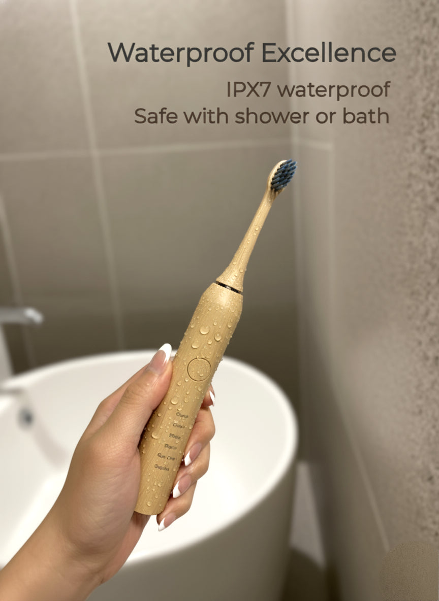 Beige electric toothbrush held by a hand with text about IPX7 waterproof rating, against a bathroom background.
