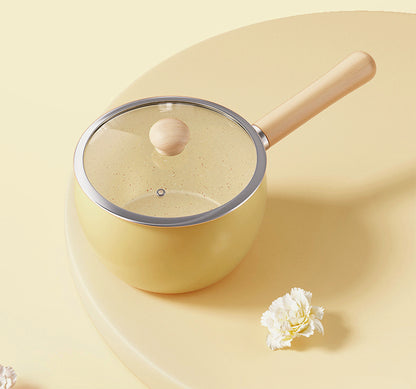 Cute and pretty yellow pot with wooden handle and lid on a light surface, solo cooking, Mini pot with Ceremic coating, non-stick.